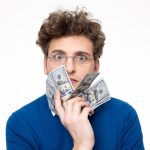 Man with money held up to his face