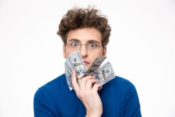 a man holding up bills to his face