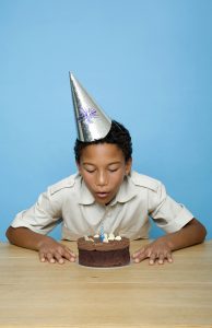 child blowing out birthday candles