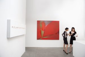 Two woman standing next to painting in a museum