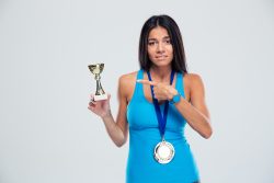 Woman with a champion cup pointing her finger at it