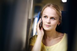 Attractive woman listening to a call on her mobile phone looking into the distance with a thoughtful expression 