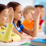 children raising their hands in class