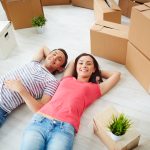 Couple laying on floor with moving boxes all around them