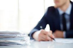 Stack of  grant documents at workplace and male employee 