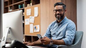 Man sitting at desk with cellphone in hand