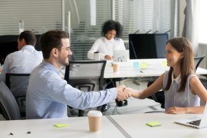 two people shaking hands at table in an office