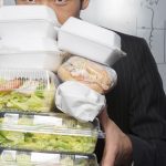 Man bringing in a stack of lunches to the office